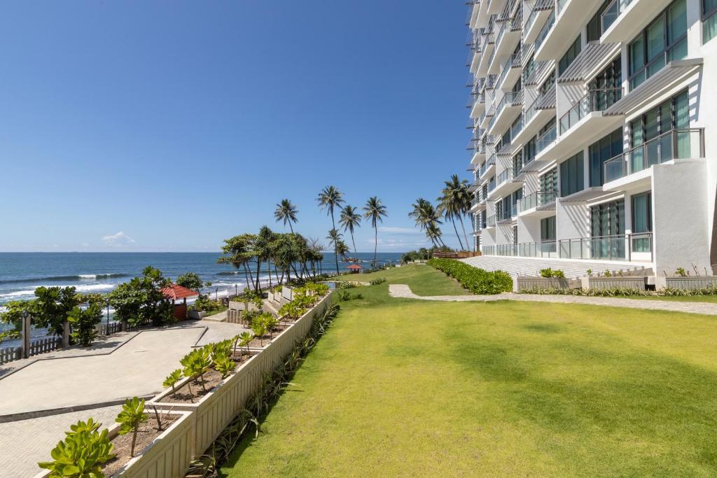 En bild på ett lägenhetshotell, som heter Oceanfront Condos. Bilden visar bottenvåningen och trädgården med havet som bakgrund.