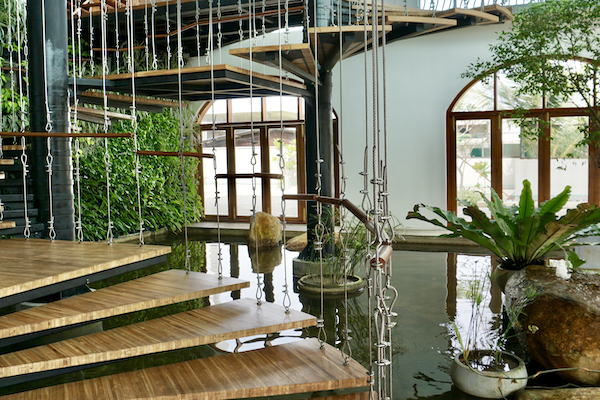 En bild på receptionen med svävande trappsteg, prydnadsdamm och växter.