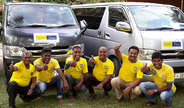 En bild på srilankanska chaufförer med svenska landslagströjor. De poserar framför minibussar med logotypen för Sophie Tours.