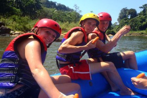 En närbild på tre personer som paddlar en gummibåt på en flod.